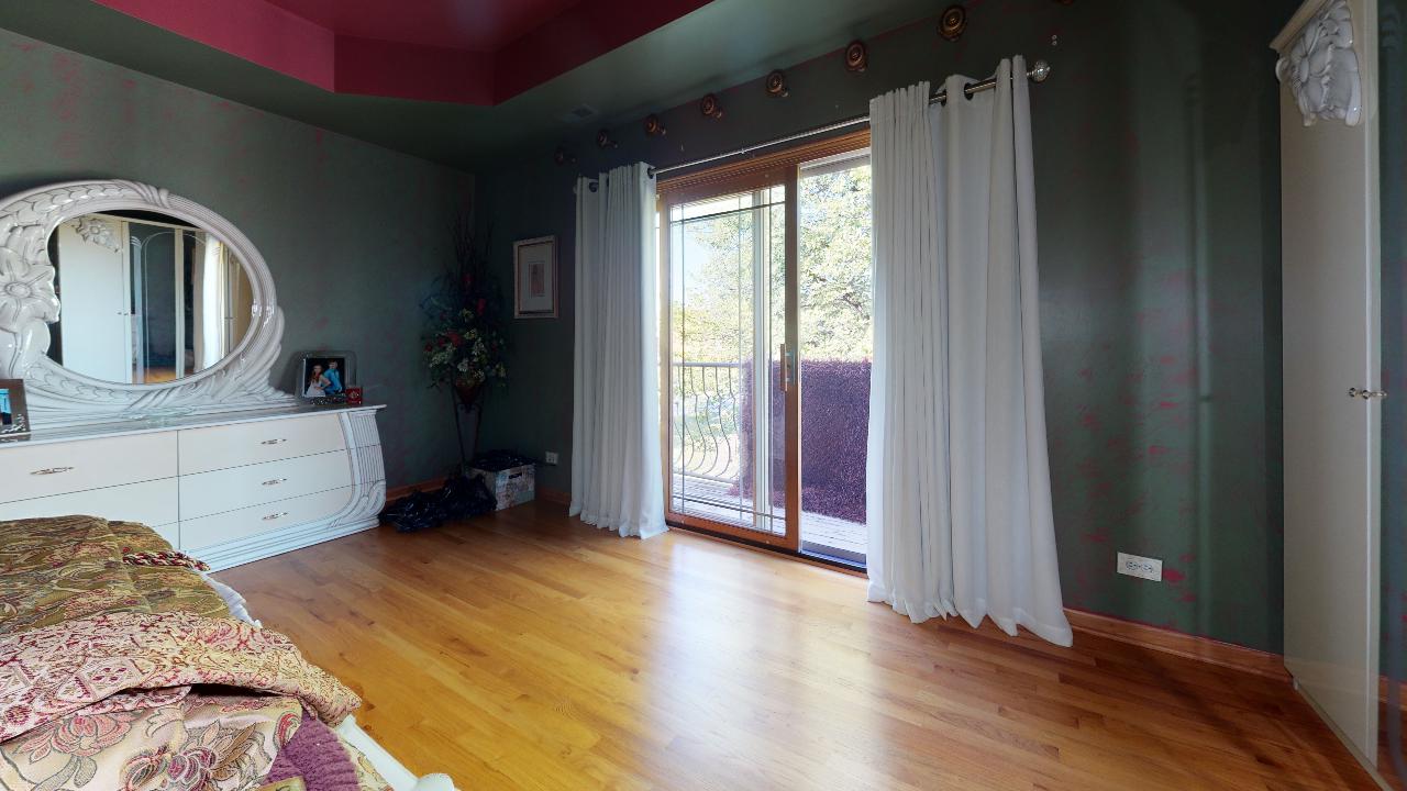 A bedroom with a bed , dresser , mirror and sliding glass doors.