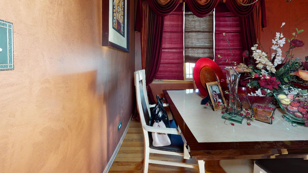 A dining room with a table and chairs and a window.