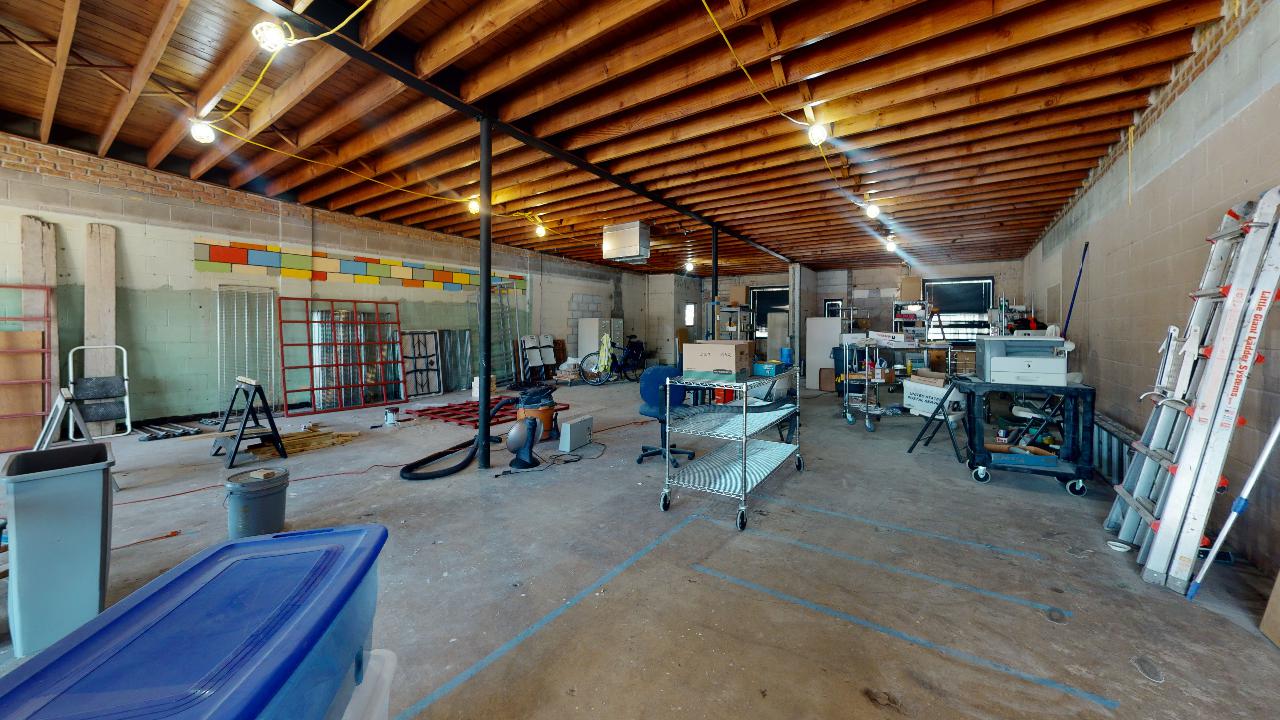 A large warehouse with wooden beams and a blue box on the floor.