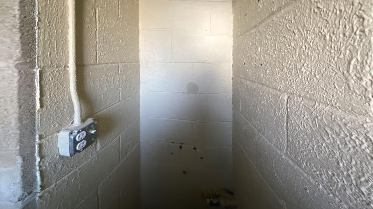 A corner of a room with a brick wall and a white tile wall.