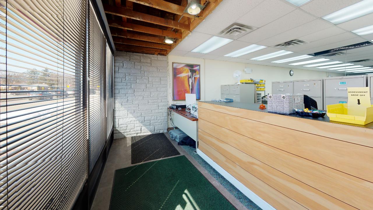 A reception area in a building with a wooden counter and a green mat.