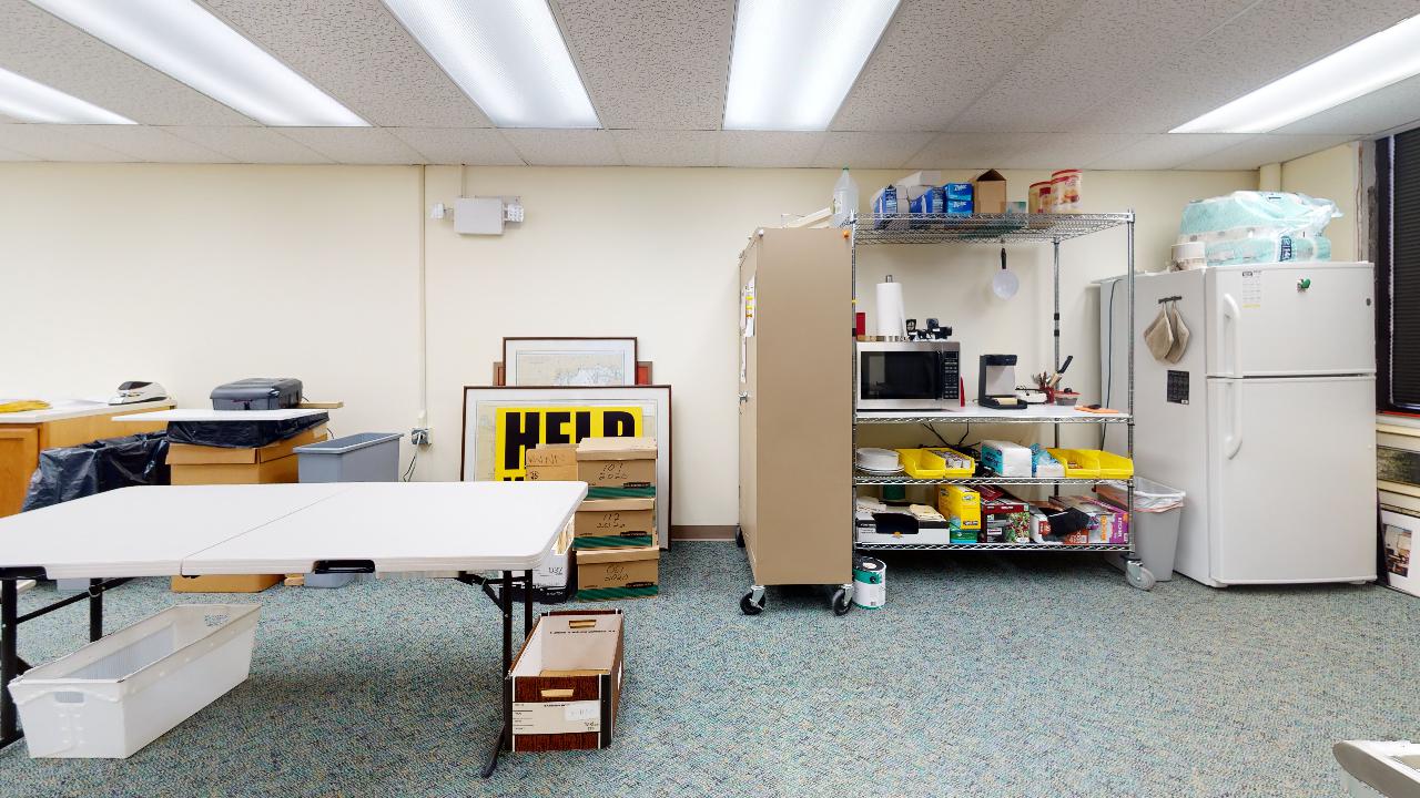 A room with a table and a refrigerator in it.