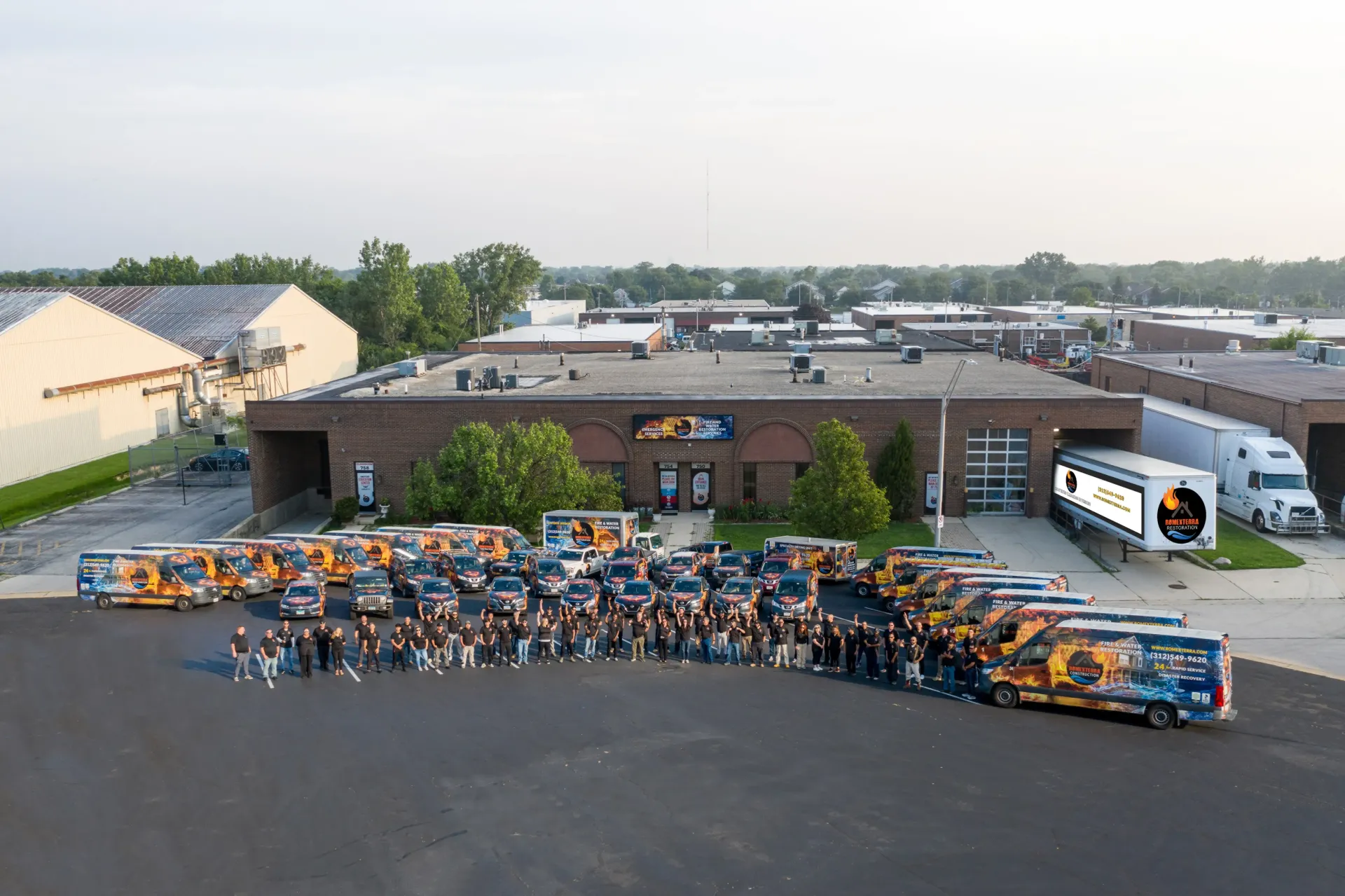 A group of men are standing in front of a row of trucks and vans.