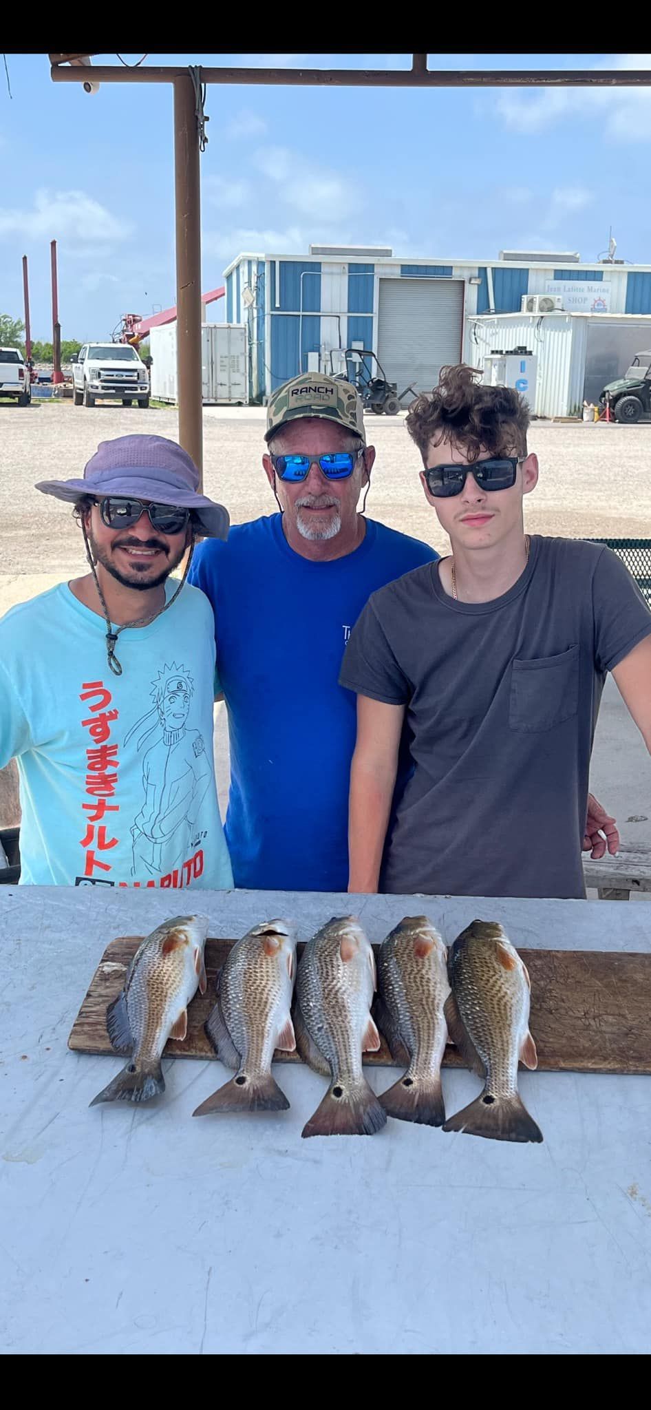 Three men are standing next to a table with fish on it.