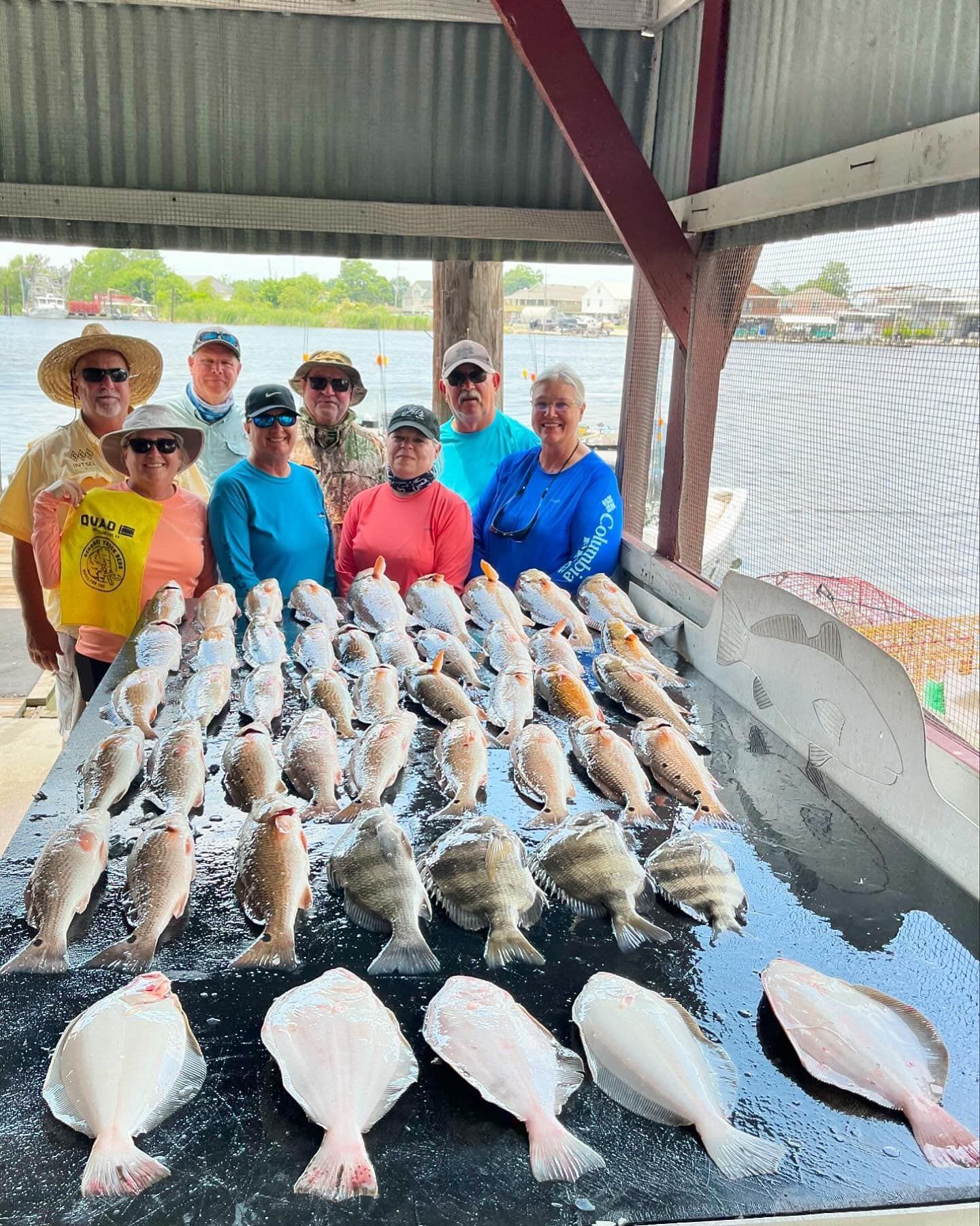 A group of people are standing around a table filled with fish.