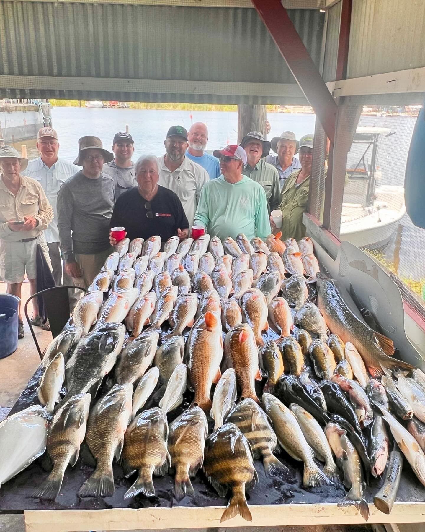 A group of men are standing around a table filled with fish.