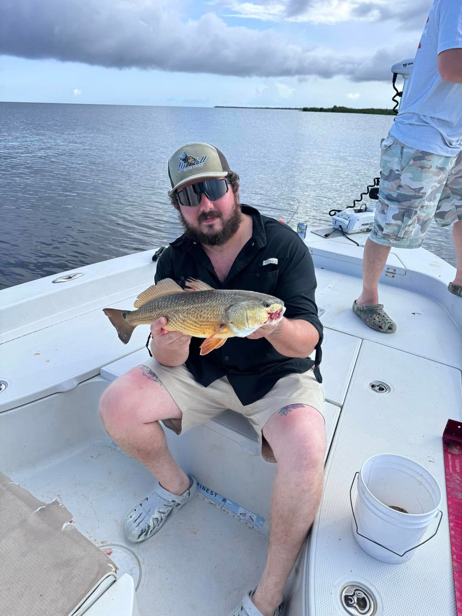 A man is sitting on a boat holding a fish.