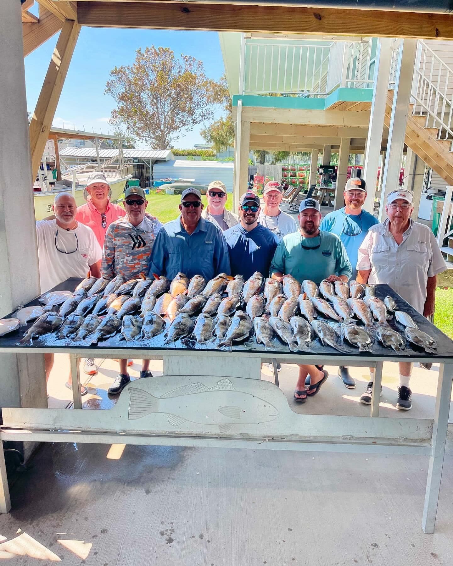 A group of men standing around a table filled with fish.