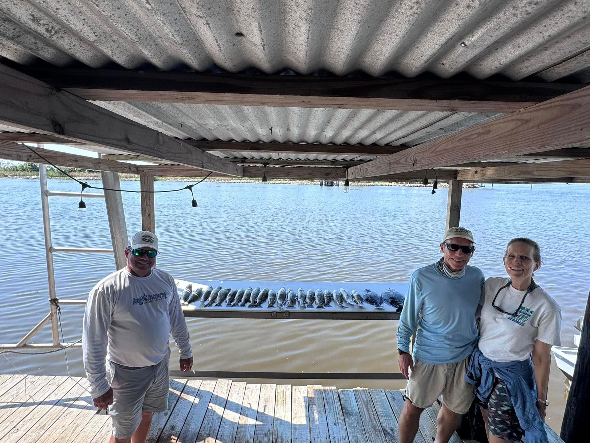 Three people are standing on a dock overlooking a body of water.