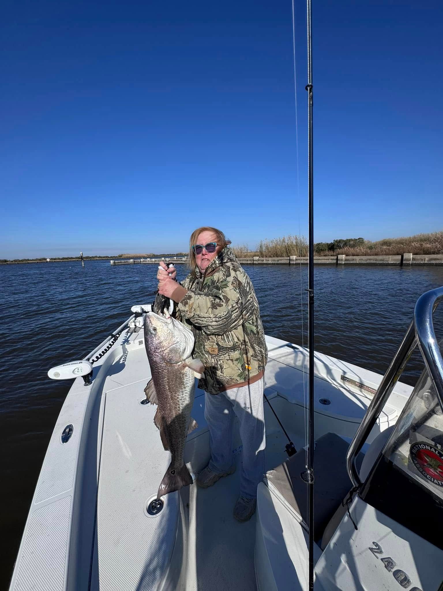 A man is sitting on the back of a boat holding a large fish.