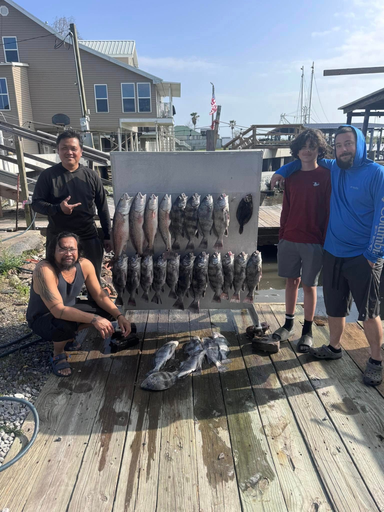 A group of men are standing next to a display of fish on a dock.