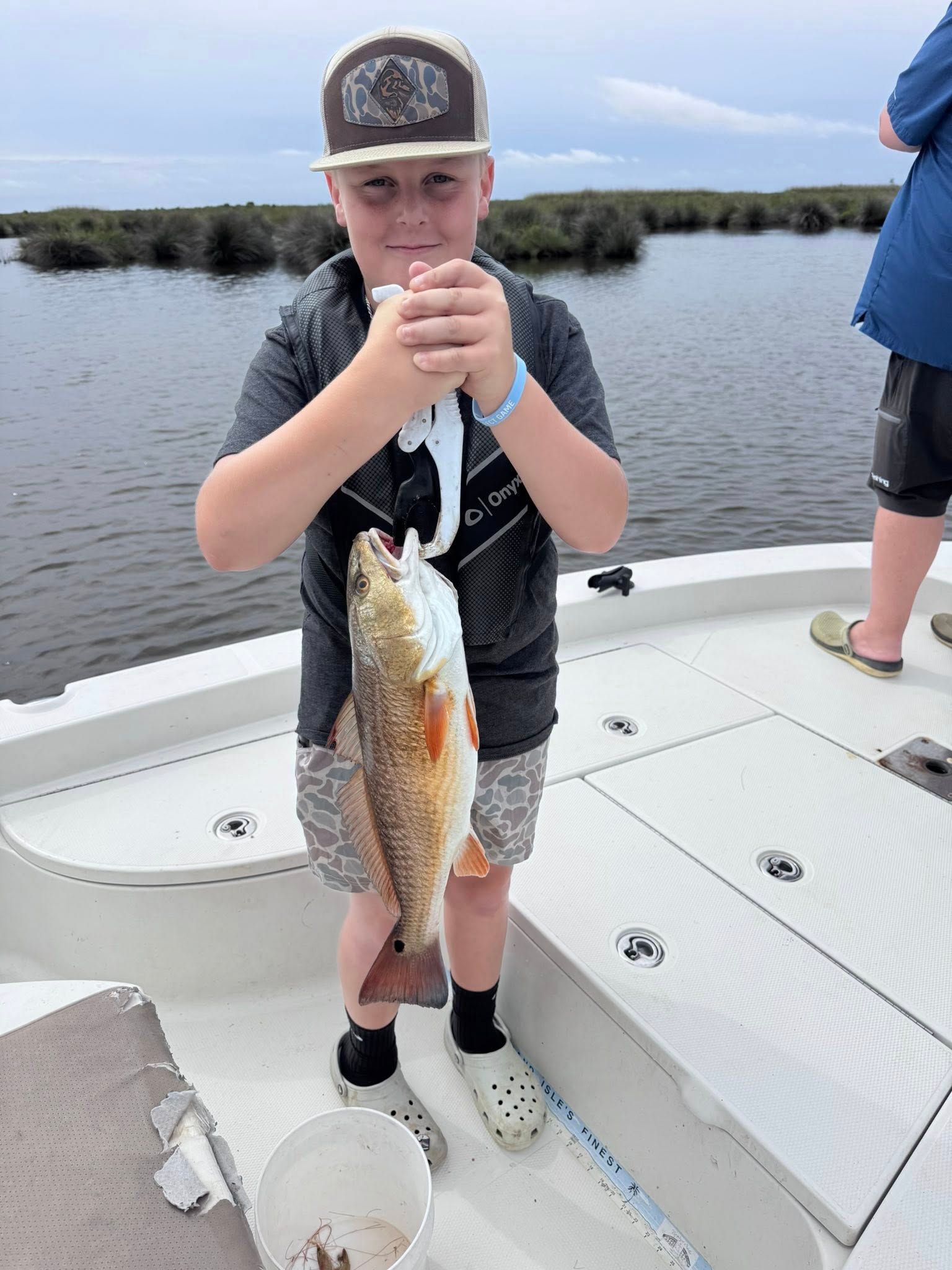 A young boy is holding a fish on a boat.