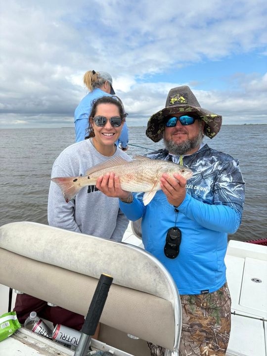 A man and a woman are holding a fish on a boat.
