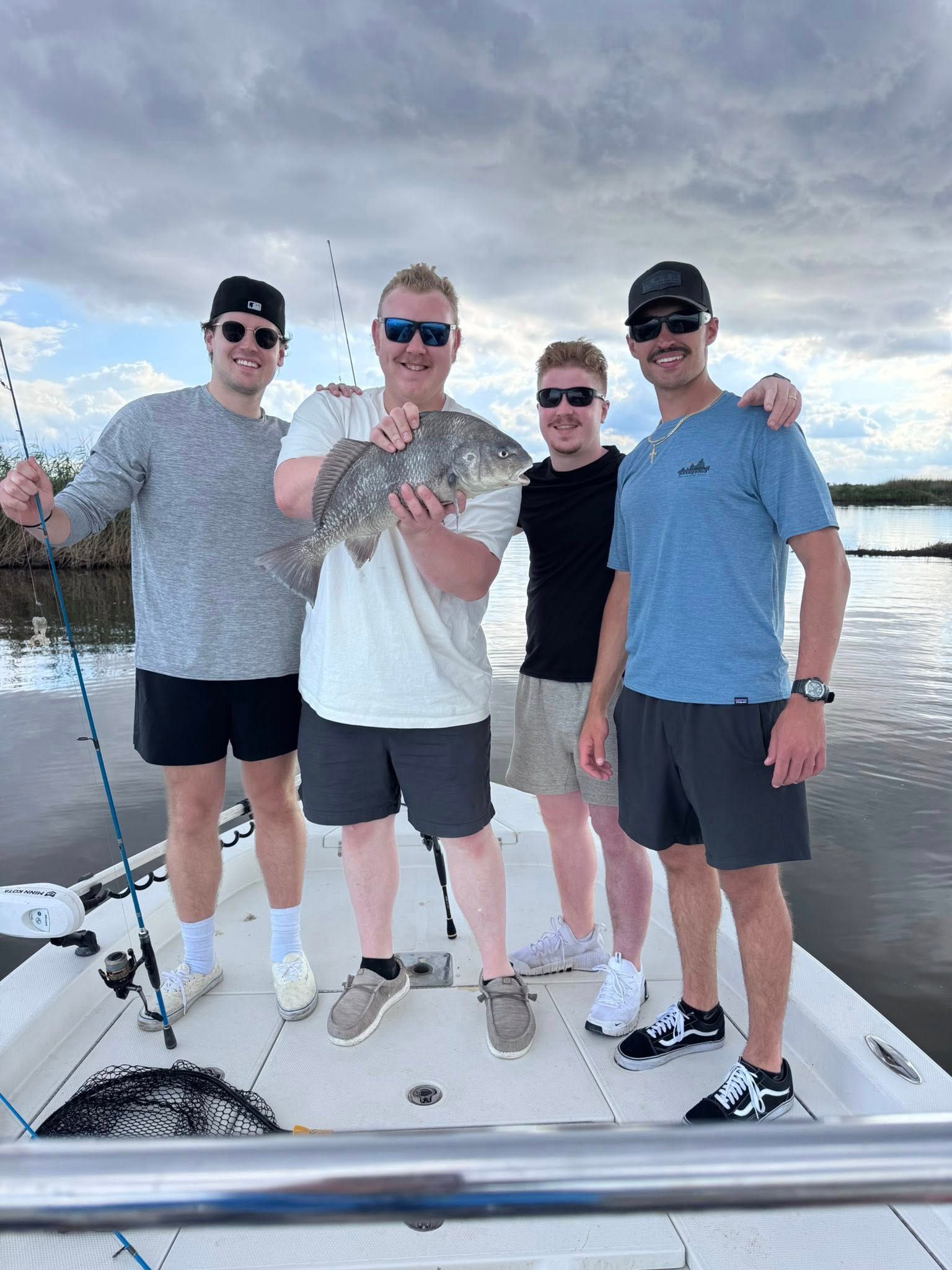 A man is standing on a boat holding a fish.