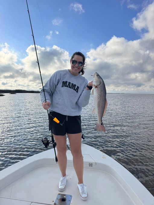 A woman is standing on a boat holding a fish.