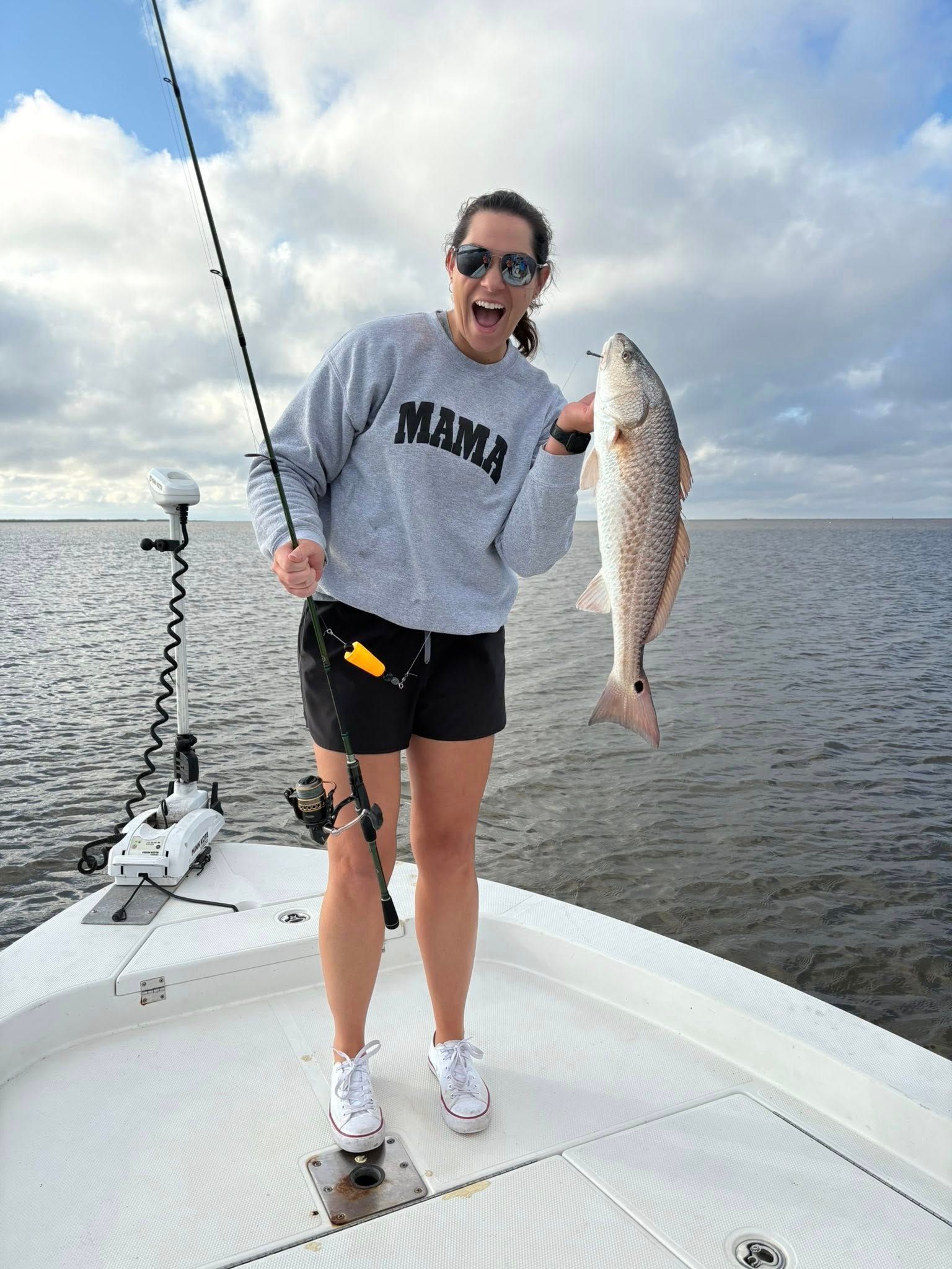 A woman is standing on a boat holding a large fish.