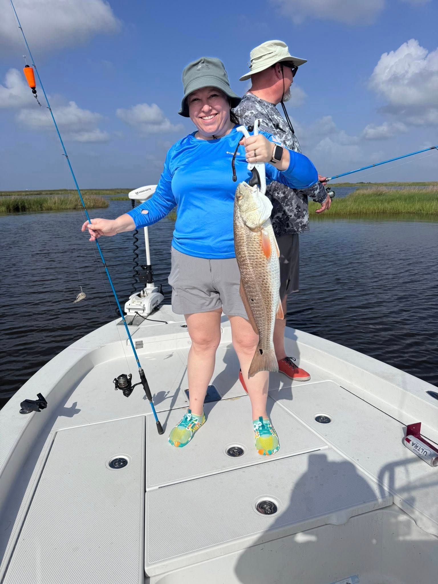 A woman is standing on a boat holding a large fish.
