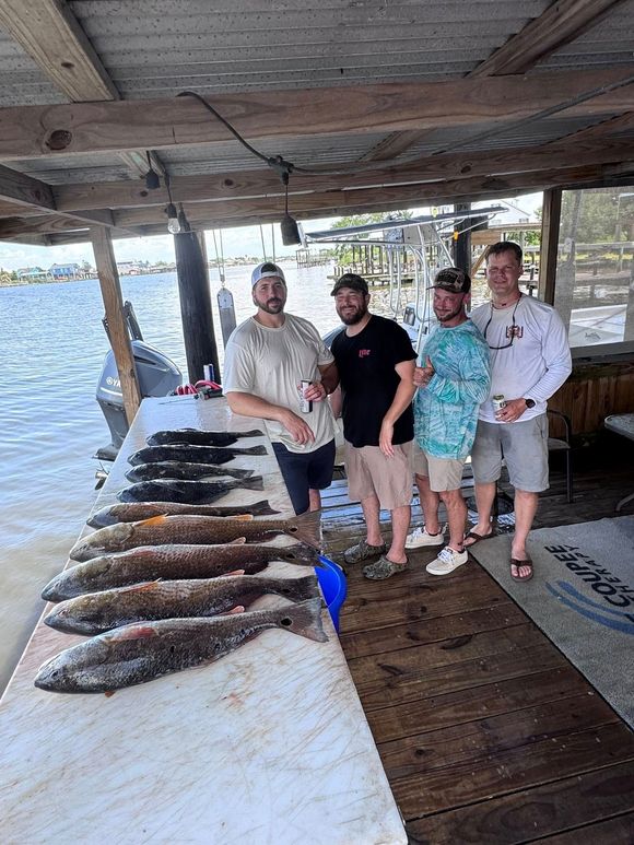 A group of men are standing next to a table full of fish.