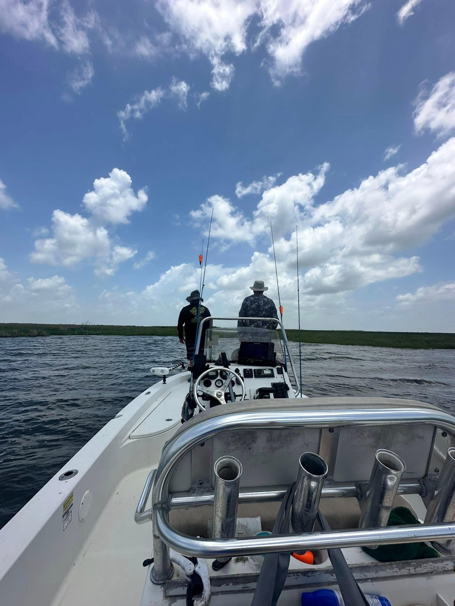A man is sitting on the back of a boat in the water.