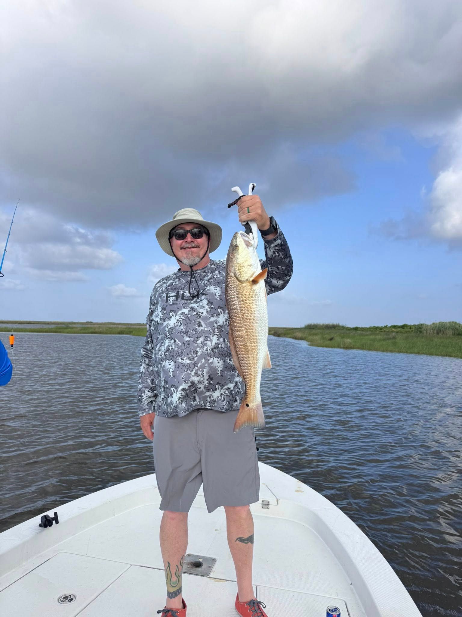 A man is standing on a boat holding a large fish.