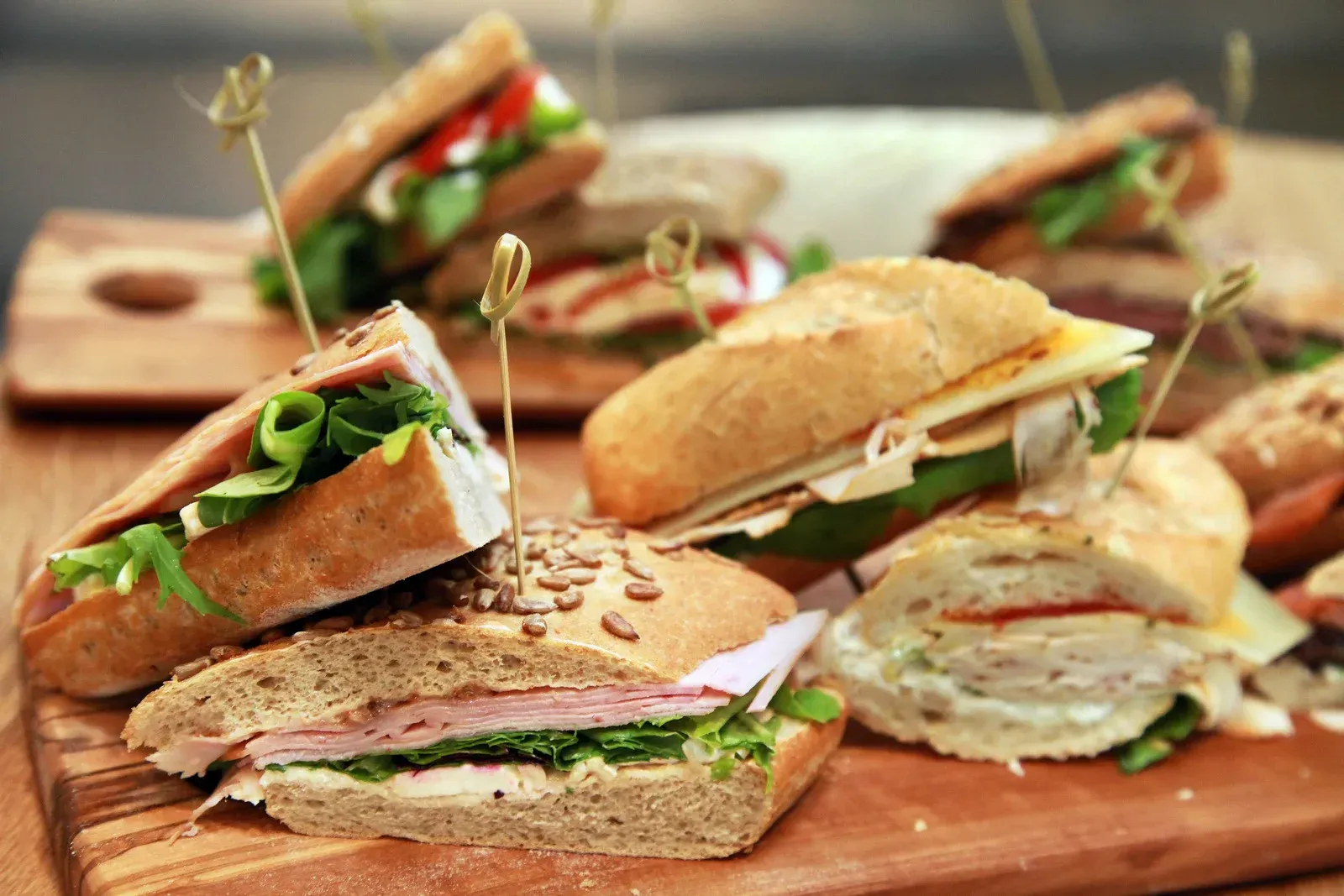 A wooden cutting board topped with sandwiches on toothpicks.