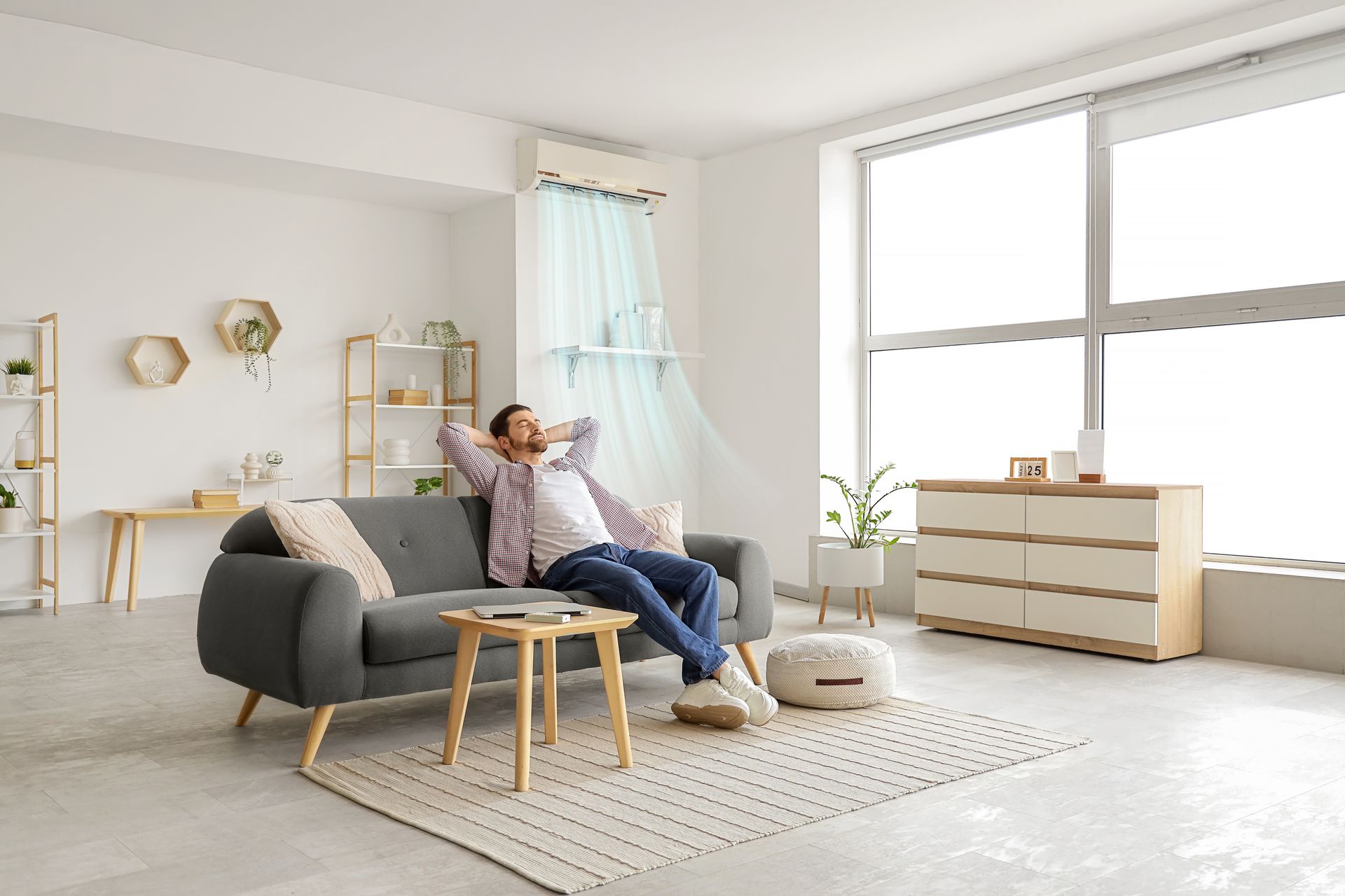 A man relaxing in a living room with an operating air conditioner.
