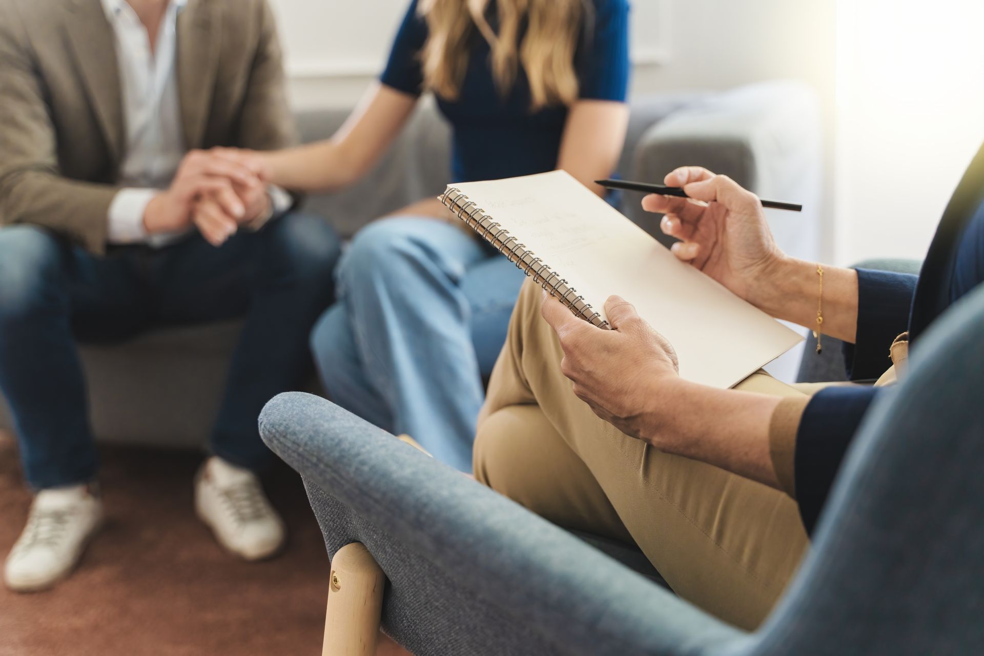 Person taking notes during a counseling or therapy session in a casual office setting