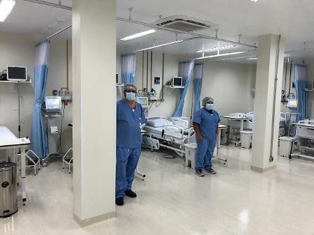 ala de hospital com camas e duas enfermeiras com mascaras e roupas azuis