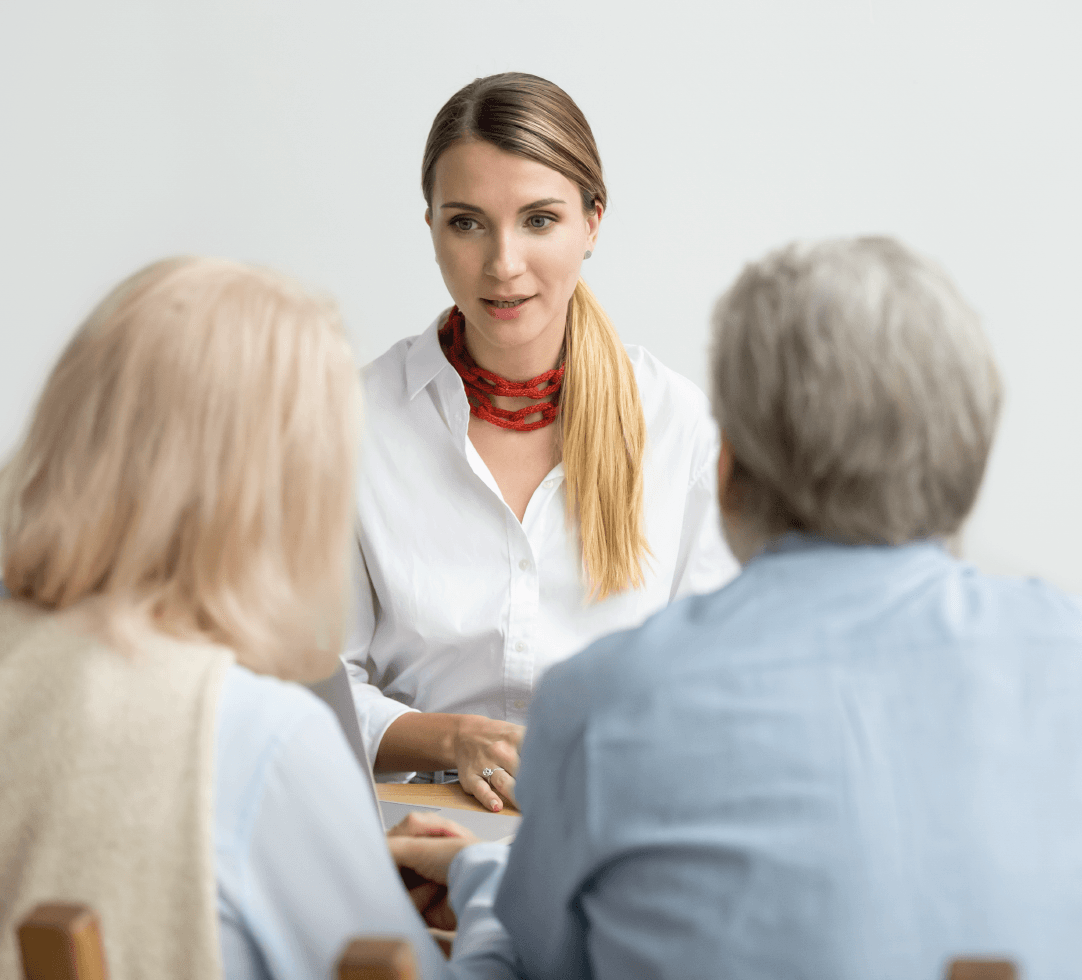 Consultora de saúde conversando com casal de idosos, simbolizando atendimento personalizado.