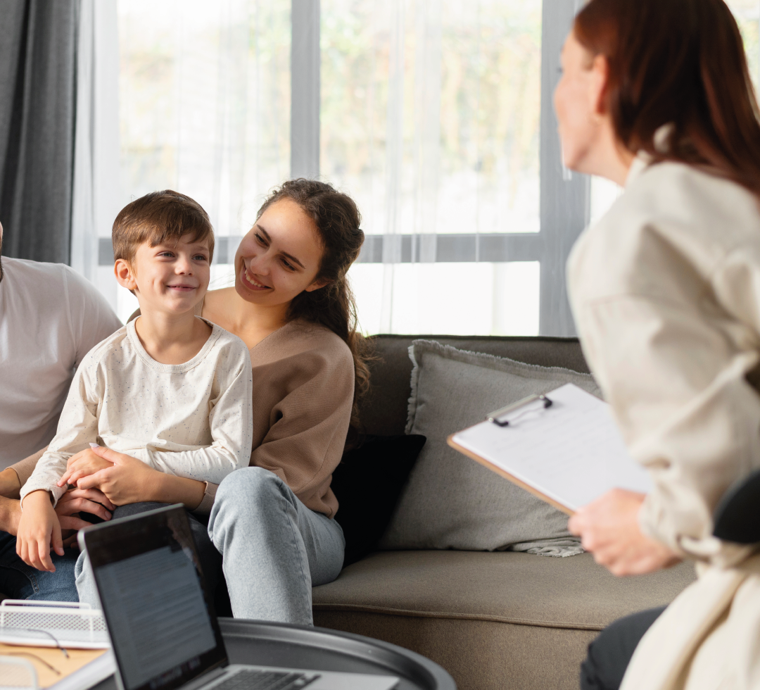 mulher com criança no colo de um sofá com consultora com prancheta