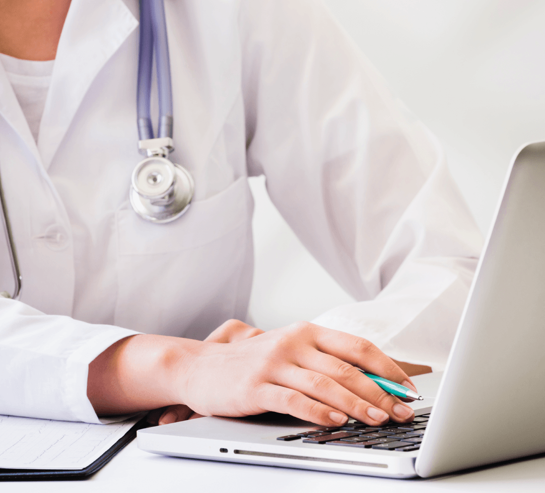 Uma médica com um estetoscópio no pescoço está digitando em um laptop