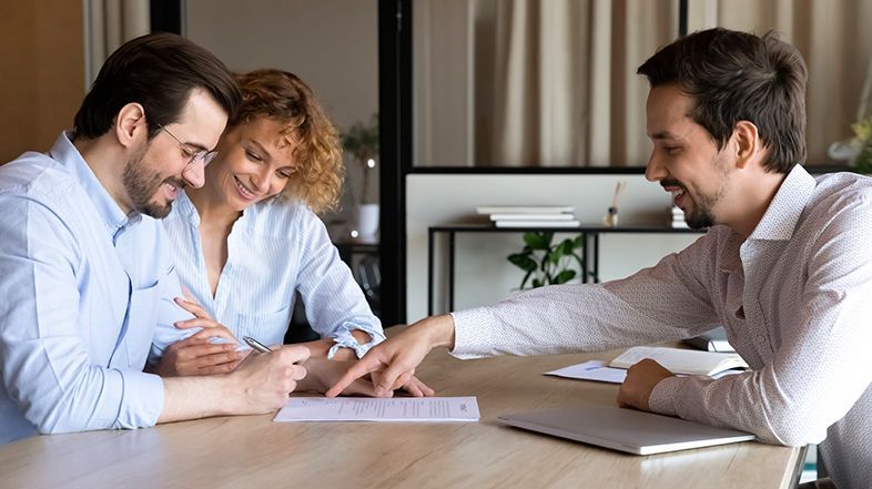 A man and a woman are sitting at a table signing a document.
