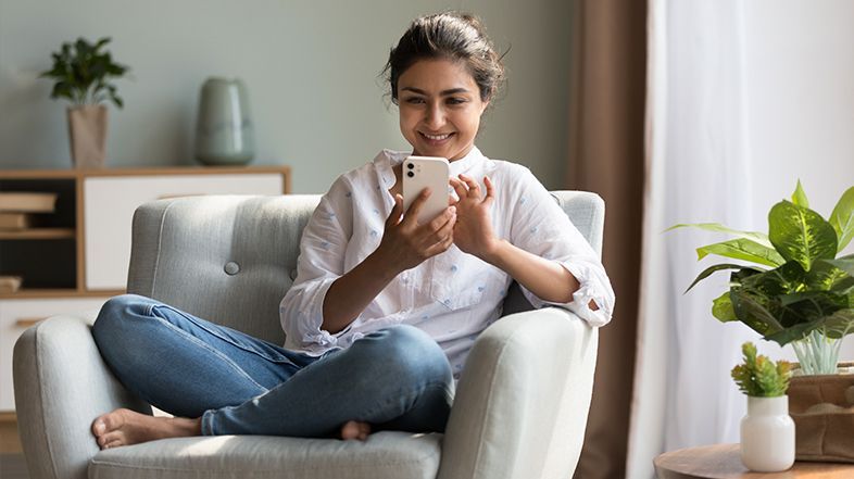 A woman is sitting in a chair looking at her cell phone.