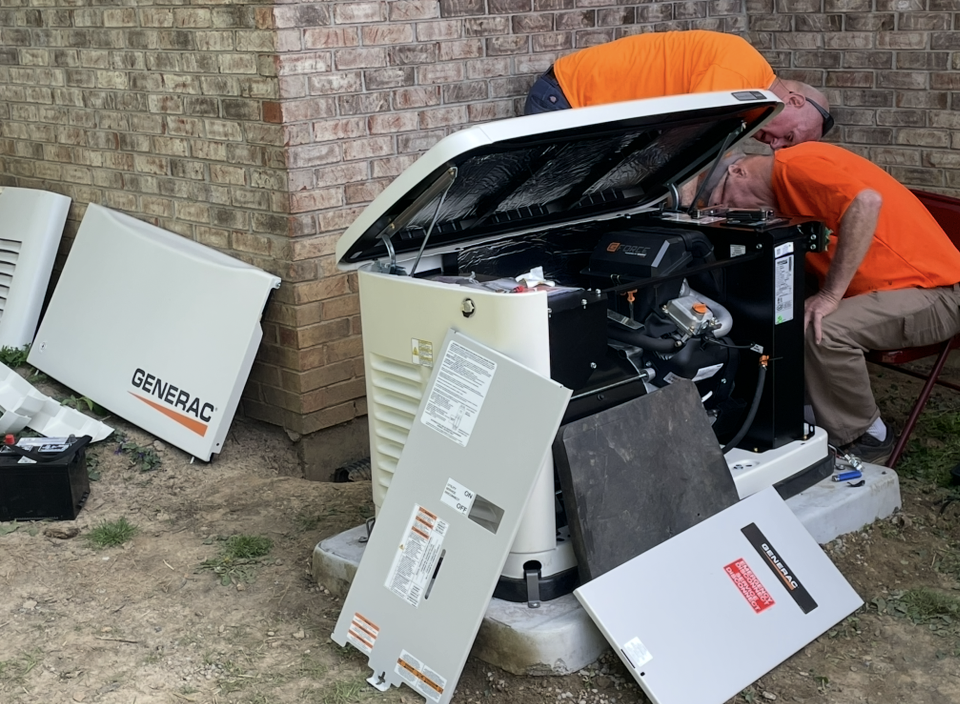 A generator is sitting in the grass in front of a house.