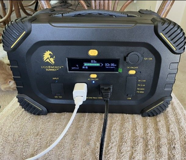 Black portable power station with digital display and plugged-in cables. Black portable power station with digital display and plugged-in cables.