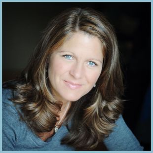A woman with long brown hair and blue eyes smiles for the camera