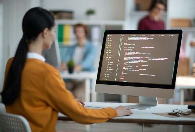 A woman is sitting at a desk working on a computer.