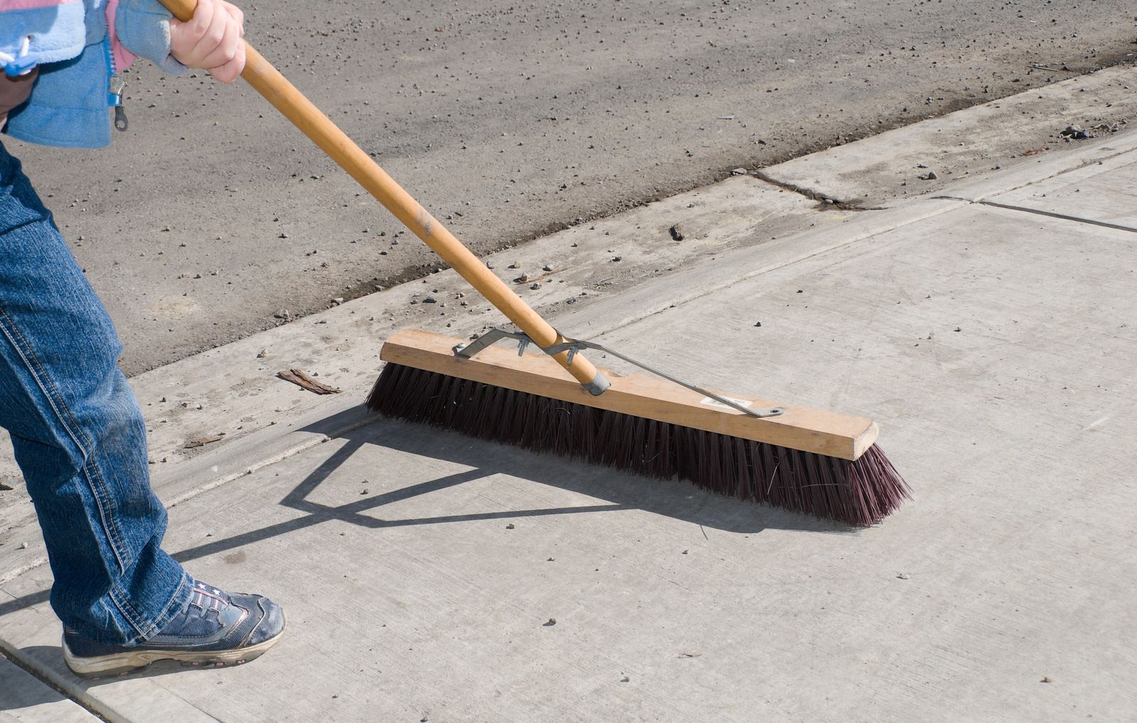 A person is sweeping the sidewalk with a broom