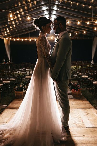 Couple standing face to face under string lights in a wedding venue at night