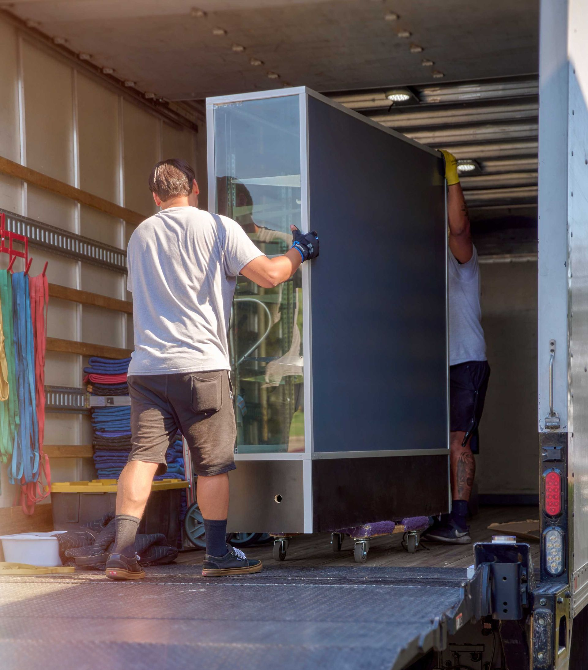 Two people loading a large aquarium into a truck.