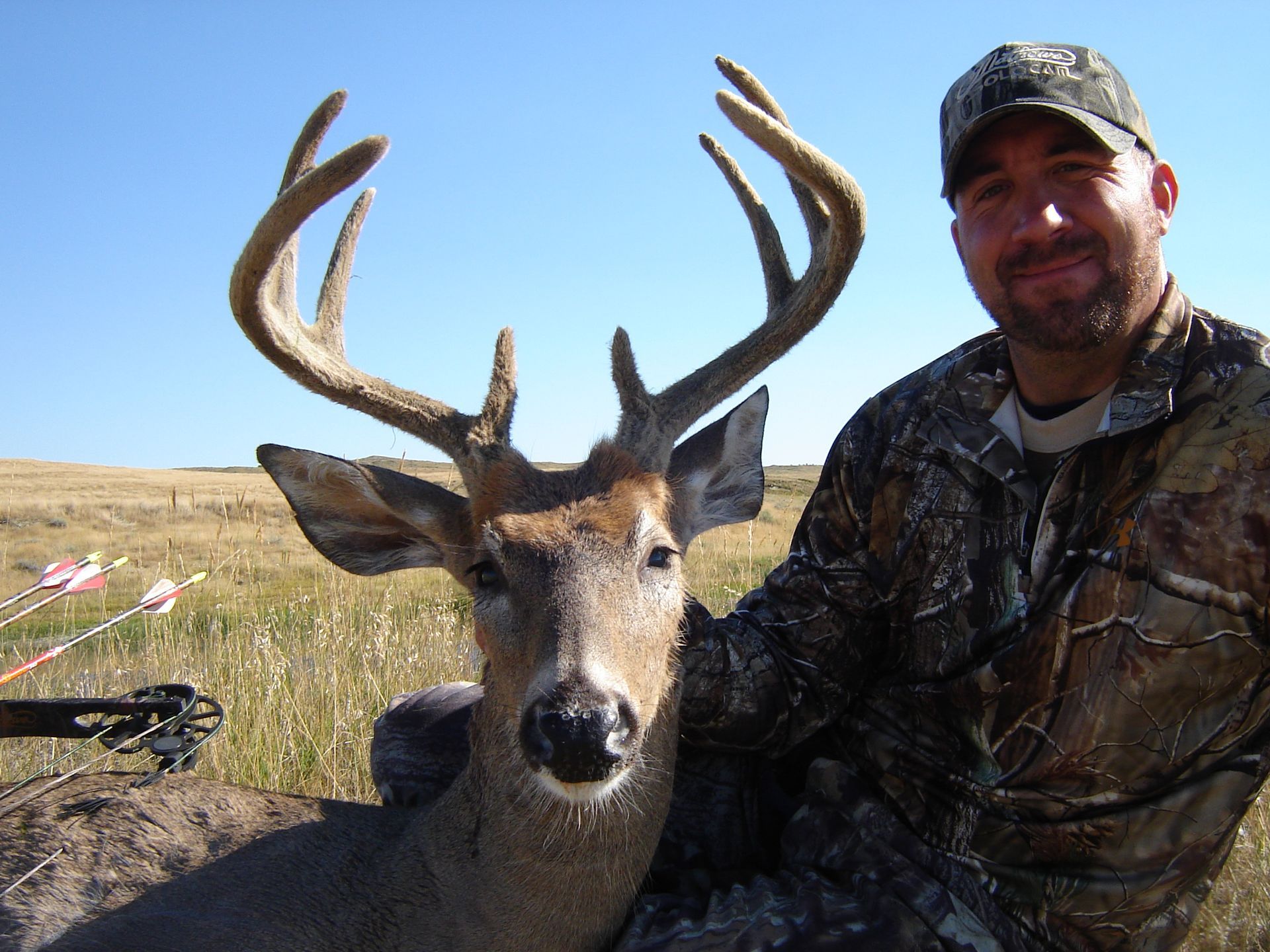 A man in a camo jacket poses with a deer
