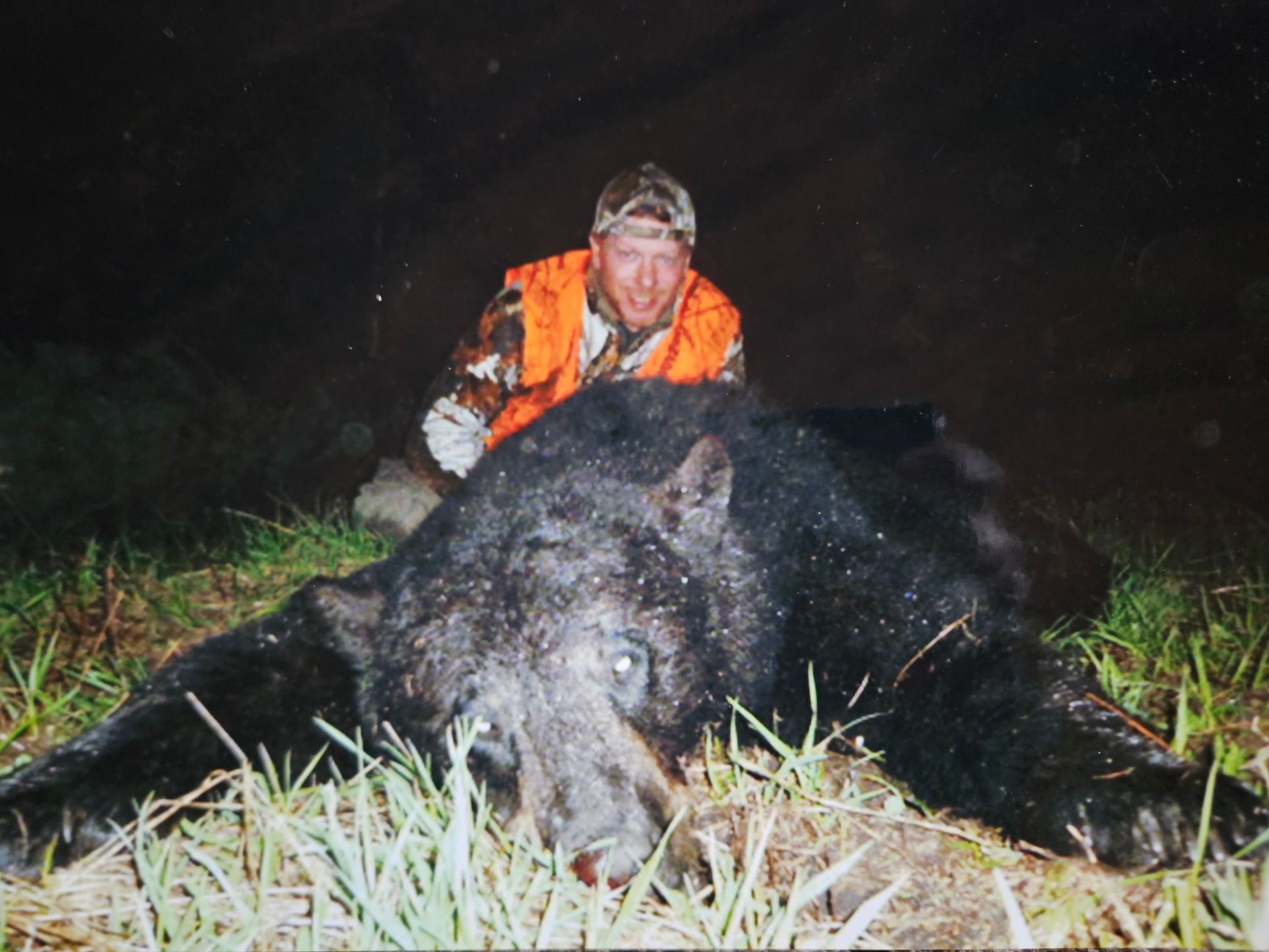 A man knelt behind a dead black bear