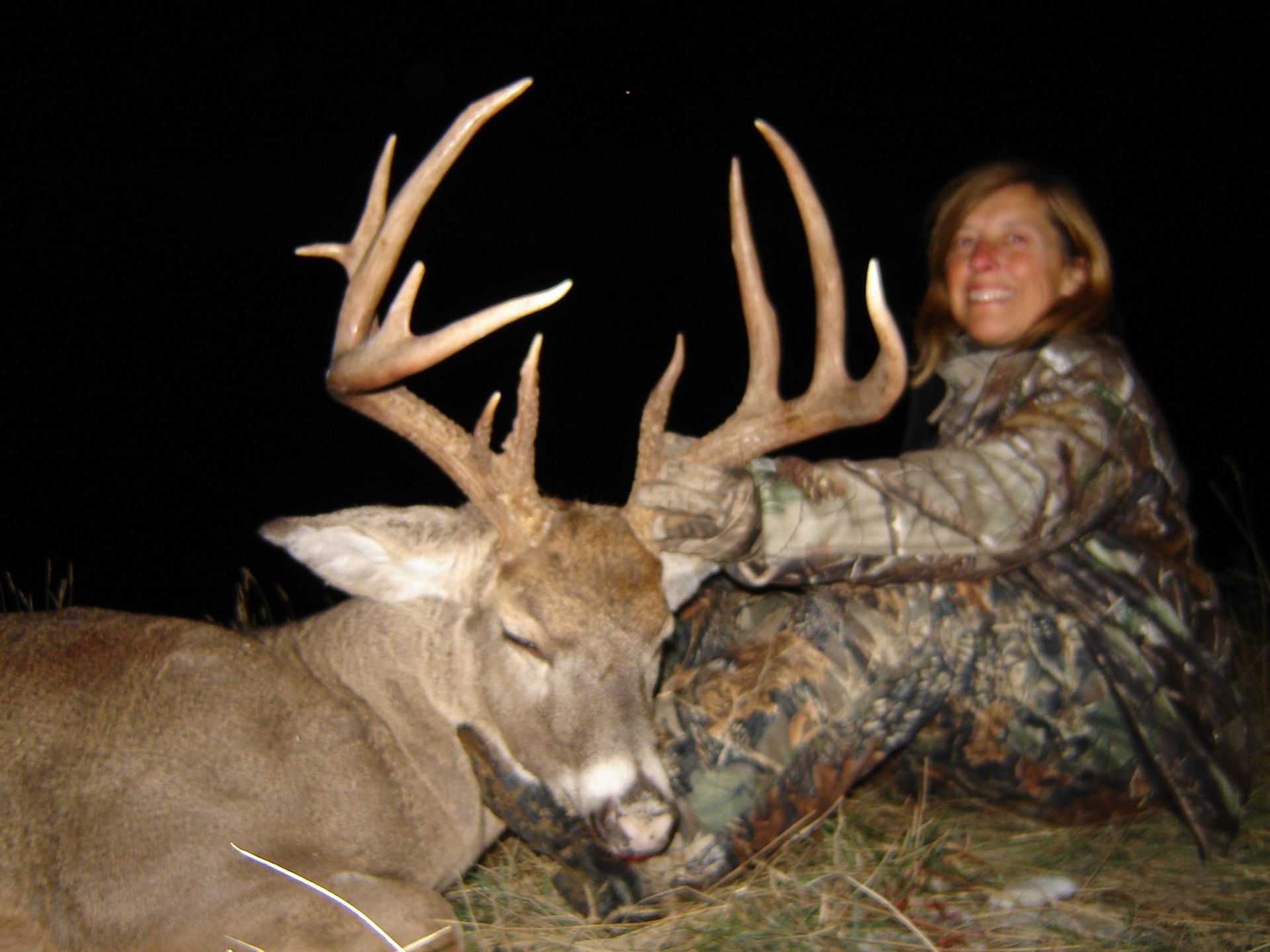 A woman is kneeling next to a large deer.