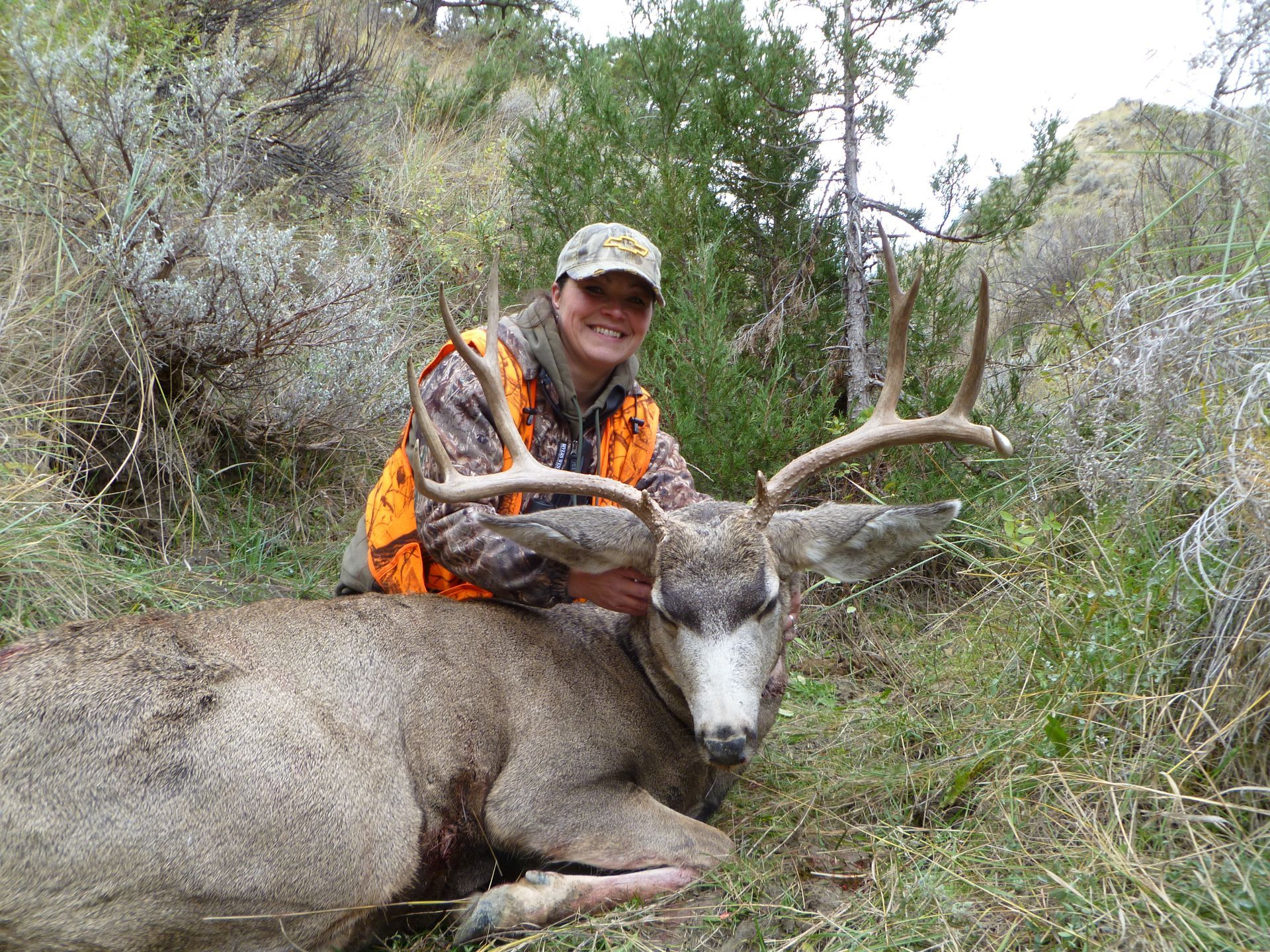 A woman holding up the head of a dead deer