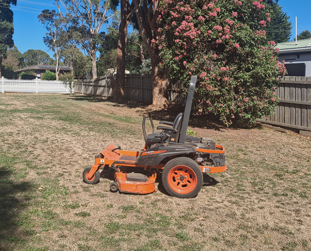 A lawn mower is parked in the middle of a lush green field.