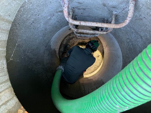 A man is crawling through a hole with a green hose.