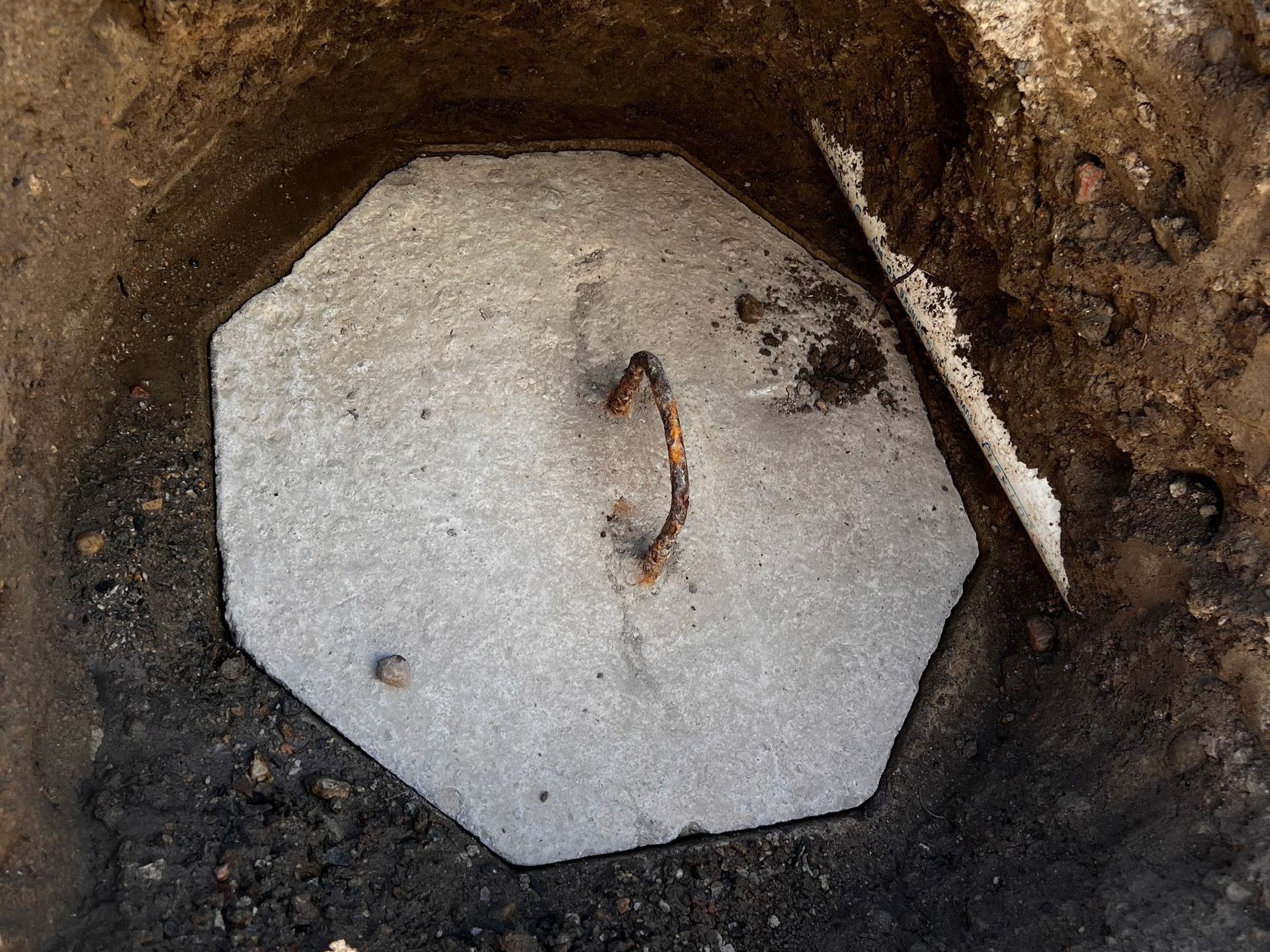 A concrete block with a handle is in the dirt