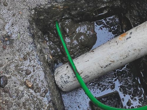 A white pipe with a green hose attached to it