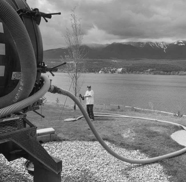 A black and white photo of a man standing in front of a lake