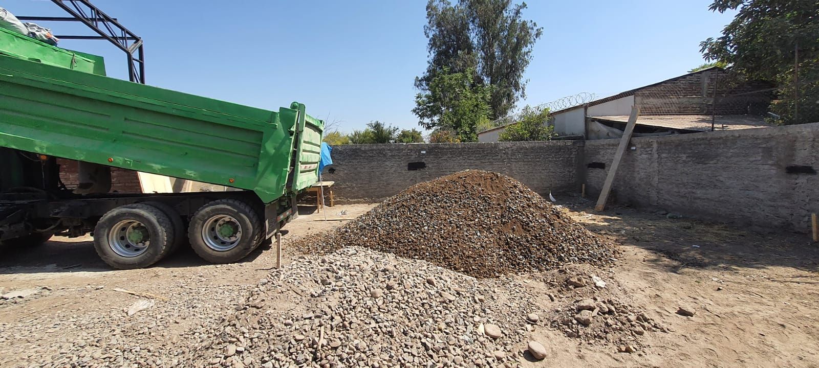 Camión arrojando grava sobre una pila en un sitio de construcción.